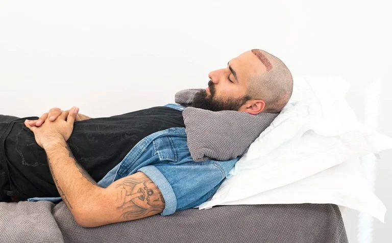 man sleeping with neck pillow after hair transplant